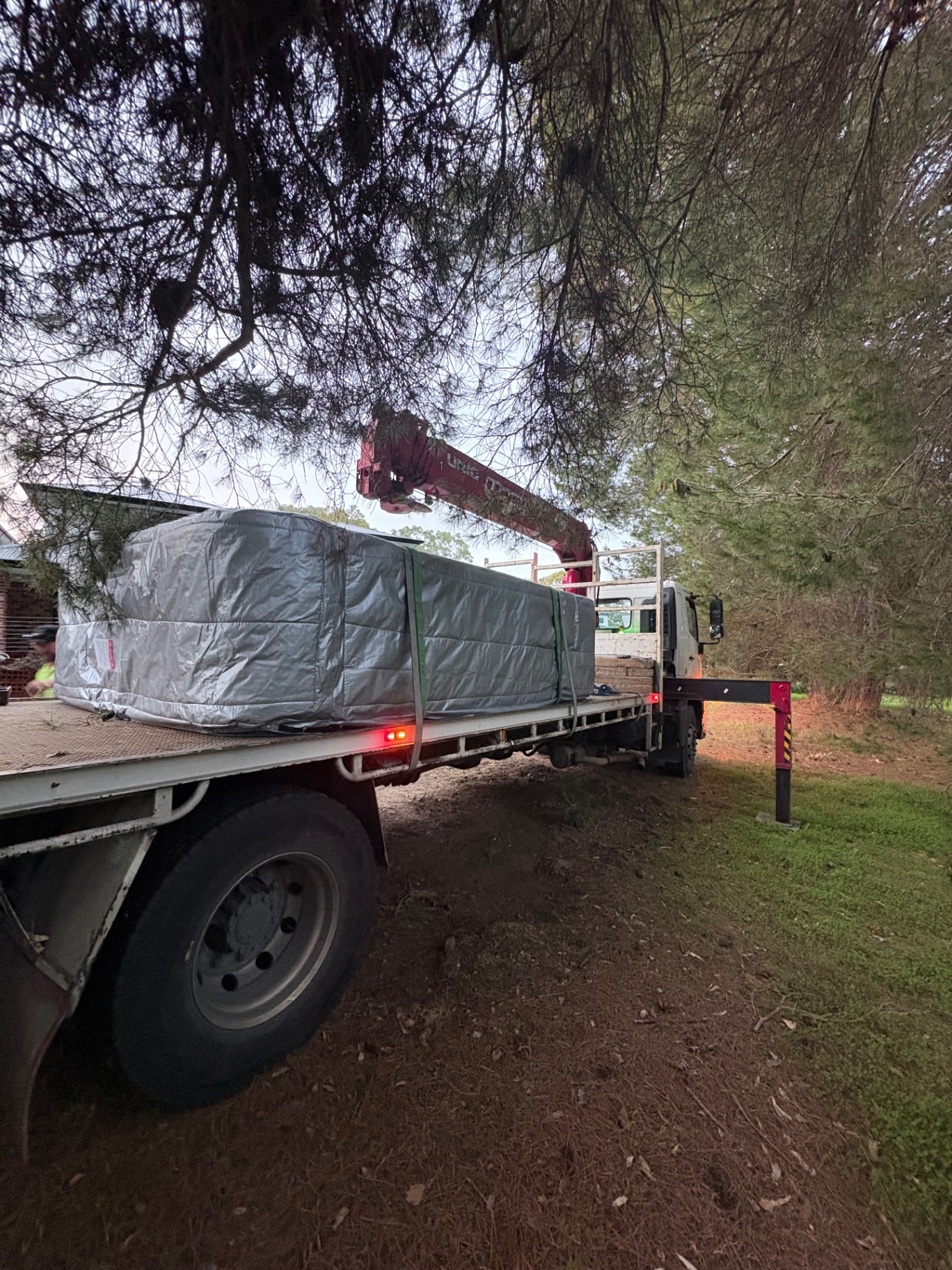 Crane truck delivering a wrapped spa